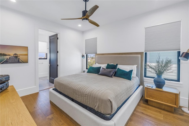 bedroom featuring ceiling fan, multiple windows, and hardwood / wood-style floors