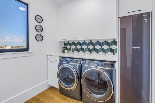 laundry room featuring separate washer and dryer and light hardwood / wood-style floors