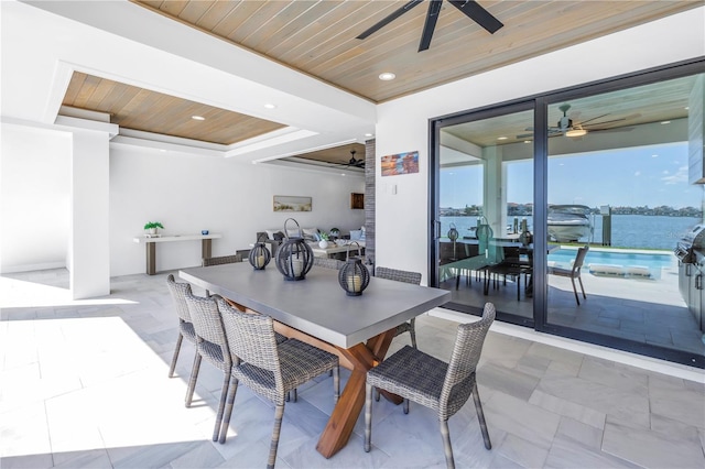 dining room with a water view, ceiling fan, a raised ceiling, and wooden ceiling