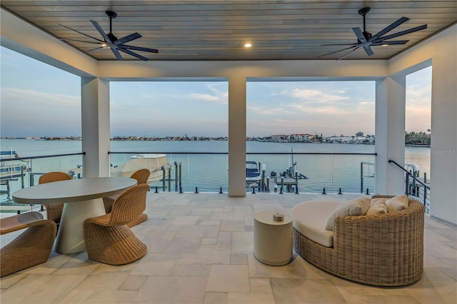 patio terrace at dusk with a water view and ceiling fan