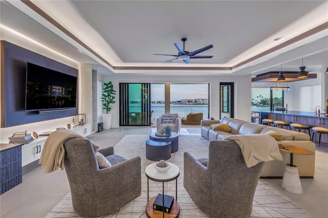 living room with ceiling fan, sink, and a raised ceiling