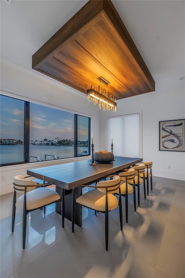 dining room featuring concrete flooring, a water view, and beamed ceiling