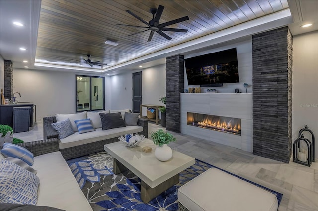 living room featuring a tiled fireplace, wooden ceiling, and ceiling fan