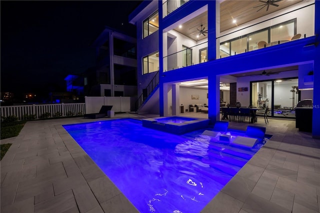 pool at night featuring a patio, an in ground hot tub, and ceiling fan