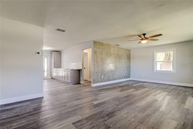 interior space with ceiling fan, dark wood-style flooring, visible vents, and baseboards