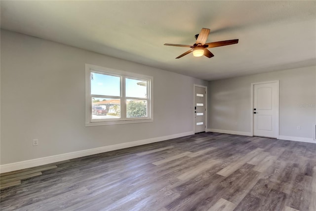 unfurnished room featuring dark wood-style flooring, a ceiling fan, and baseboards