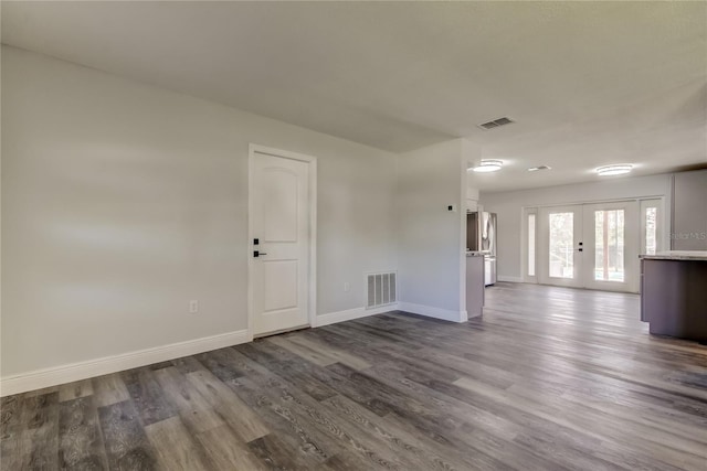 empty room featuring dark wood-style floors, french doors, visible vents, and baseboards