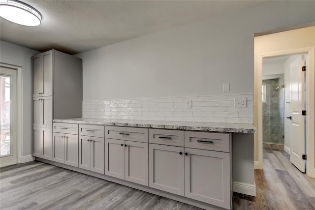 kitchen featuring gray cabinets, light stone countertops, and light wood-style floors