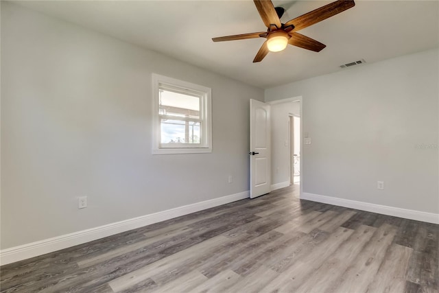 spare room with dark wood-style floors, ceiling fan, visible vents, and baseboards