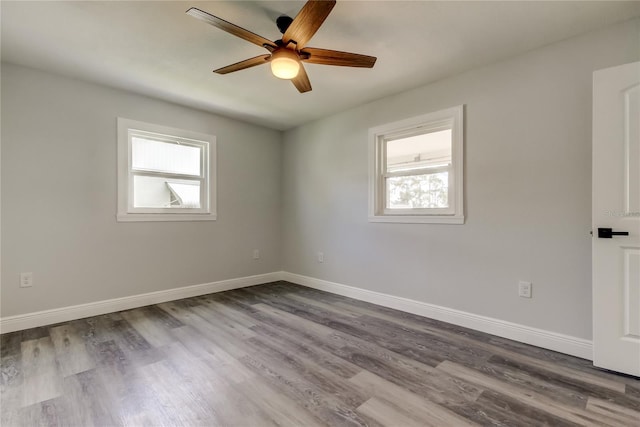 spare room with dark wood-style flooring, a ceiling fan, and baseboards