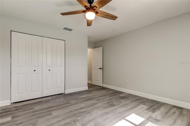 unfurnished bedroom featuring a closet, visible vents, baseboards, and wood finished floors