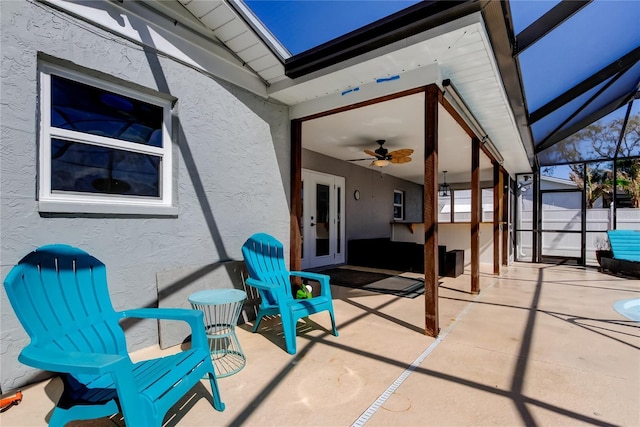 view of patio featuring french doors, glass enclosure, and ceiling fan