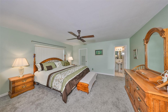 bedroom with connected bathroom, baseboards, light colored carpet, and ceiling fan