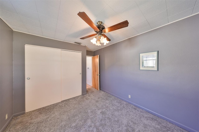 unfurnished bedroom featuring ornamental molding, carpet, visible vents, a ceiling fan, and a closet