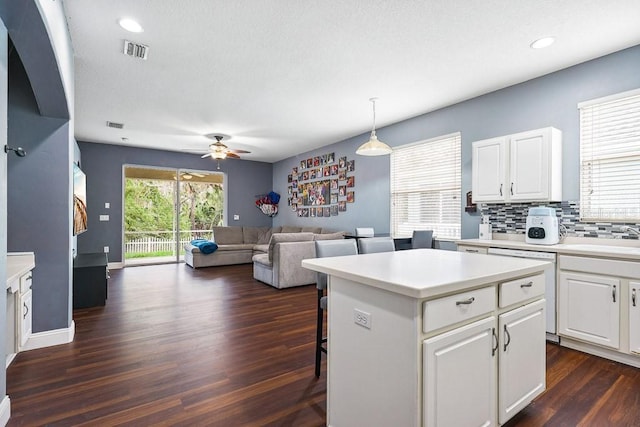 kitchen featuring a center island, white cabinetry, a kitchen breakfast bar, and decorative light fixtures