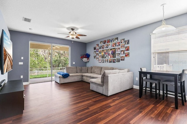 living room with dark wood-type flooring and ceiling fan