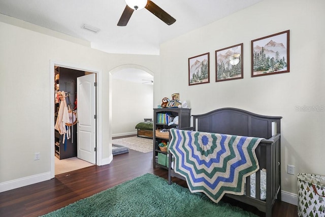 bedroom featuring ceiling fan, a spacious closet, and dark hardwood / wood-style flooring