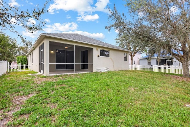 rear view of house featuring a yard and a sunroom