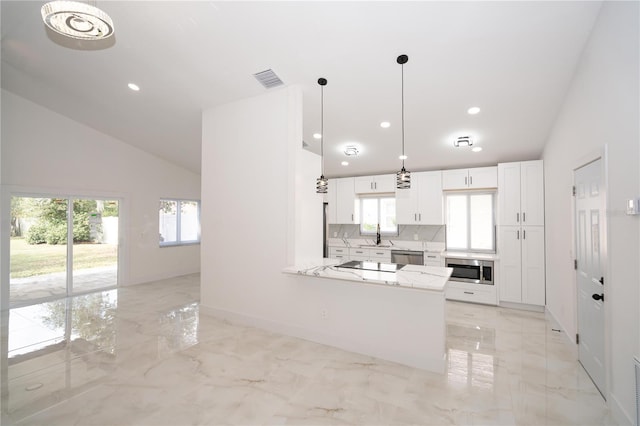 kitchen with hanging light fixtures, stainless steel dishwasher, kitchen peninsula, light stone countertops, and white cabinets