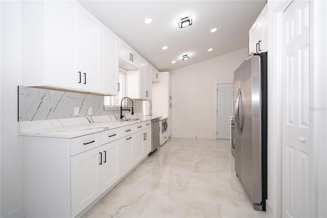 kitchen with light stone counters, stainless steel appliances, sink, and white cabinets