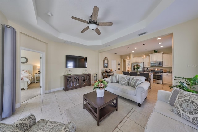 tiled living room featuring ceiling fan and a tray ceiling