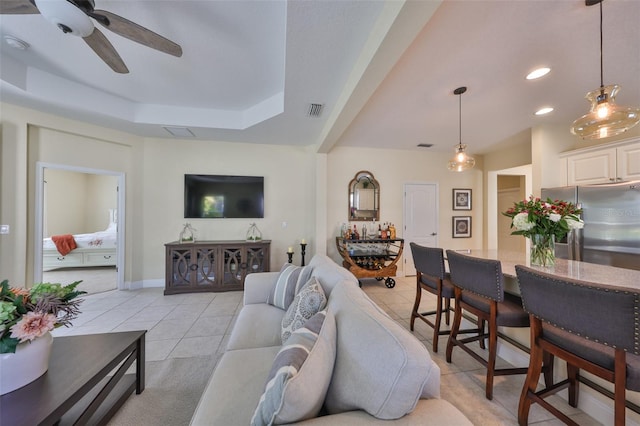 tiled living room featuring a tray ceiling and ceiling fan