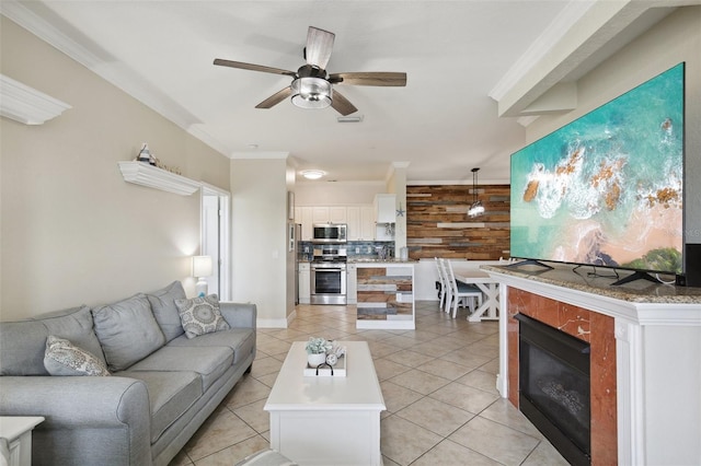 tiled living room with ornamental molding and ceiling fan