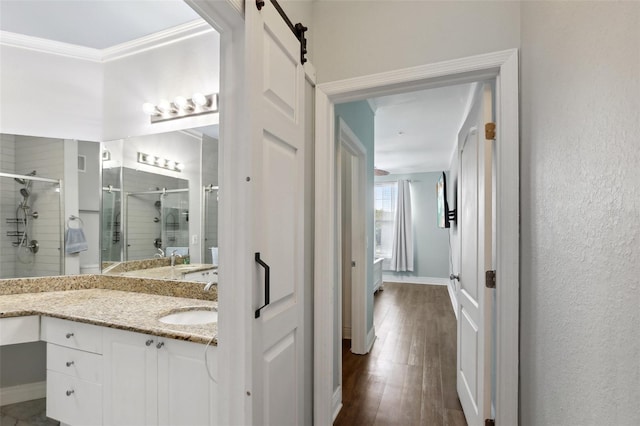 bathroom featuring hardwood / wood-style flooring, walk in shower, crown molding, and vanity