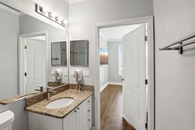bathroom with toilet, hardwood / wood-style flooring, crown molding, and vanity