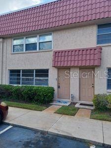 multi unit property featuring stucco siding, a tile roof, and mansard roof