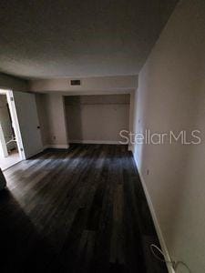 hall with dark wood-style flooring and baseboards