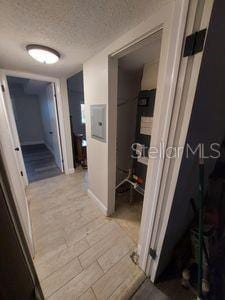 hallway featuring a textured ceiling and light wood finished floors