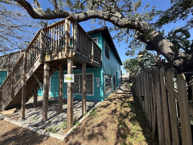 725 1st St, Indian Rocks Beach, FL 33785 - view of side of property with fence, stairway, and a wooden deck