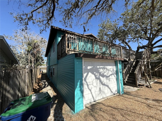 725 1st St, Indian Rocks Beach, FL 33785 - view of side of home with a garage, stairway, fence, a deck, and driveway