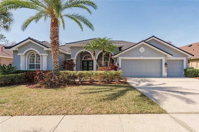 view of front of property with a garage, a front yard, driveway, and stucco siding