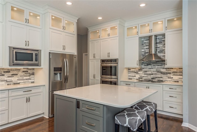 10537 Greensprings Dr, Tampa, FL 33626 - kitchen with appliances with stainless steel finishes, wall chimney exhaust hood, recessed lighting, a kitchen island, and white cabinetry