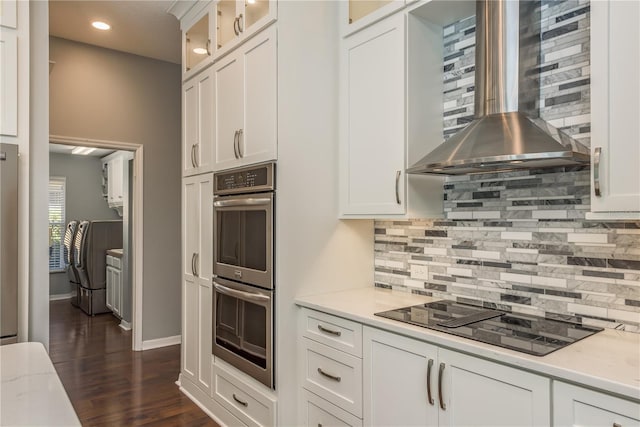 10537 Greensprings Dr, Tampa, FL 33626 - kitchen with wall chimney exhaust hood, black electric cooktop, double oven, decorative backsplash, and white cabinetry