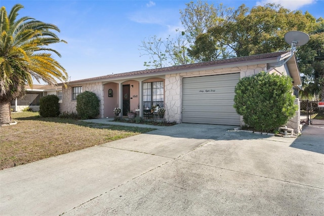 single story home with driveway, stone siding, an attached garage, and a front yard