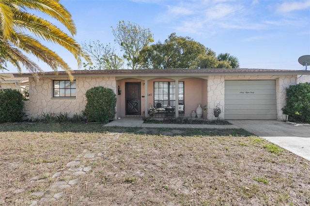 ranch-style house with an attached garage, stone siding, covered porch, and concrete driveway