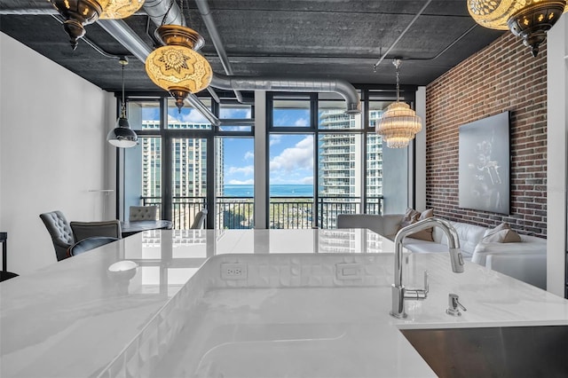 interior space featuring sink, plenty of natural light, light stone countertops, and brick wall