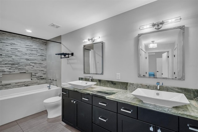 full bathroom with toilet, vanity, and tiled shower / bath