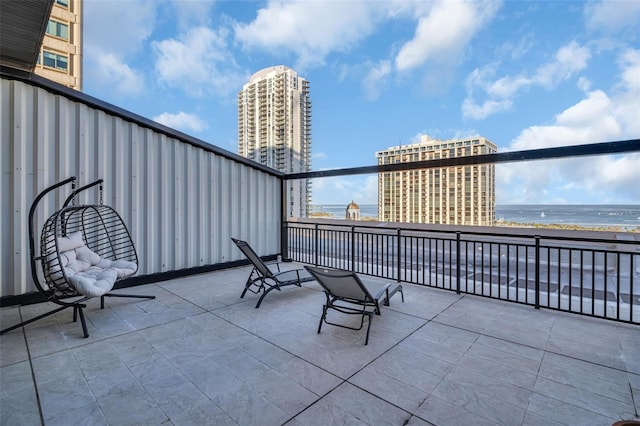 view of patio / terrace featuring a balcony, a water view, and a view of the beach