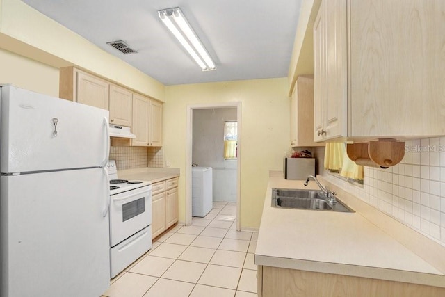 kitchen featuring tasteful backsplash, washer / dryer, sink, light tile patterned floors, and white appliances