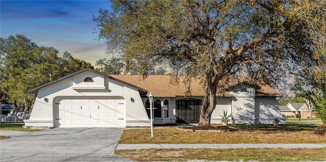 ranch-style home with a garage and a yard