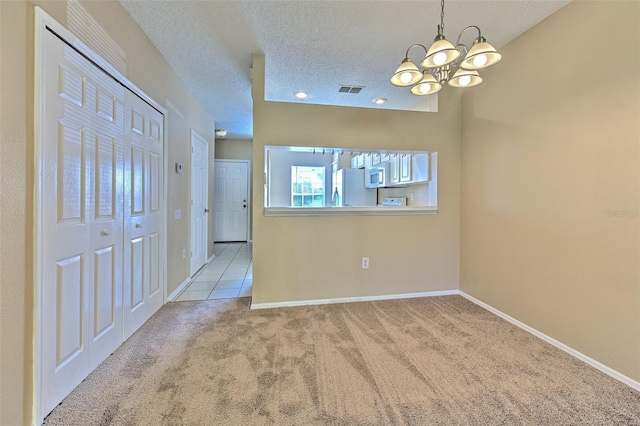 carpeted spare room featuring a chandelier and a textured ceiling