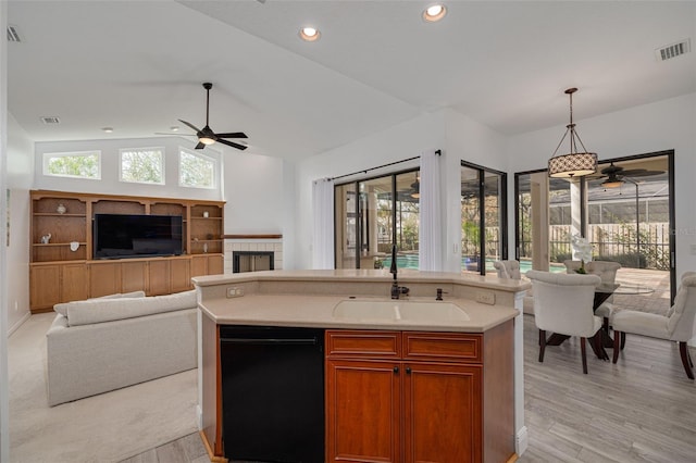 kitchen with a center island with sink, vaulted ceiling, sink, light hardwood / wood-style flooring, and decorative light fixtures