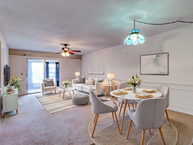 carpeted dining space with ceiling fan and a textured ceiling