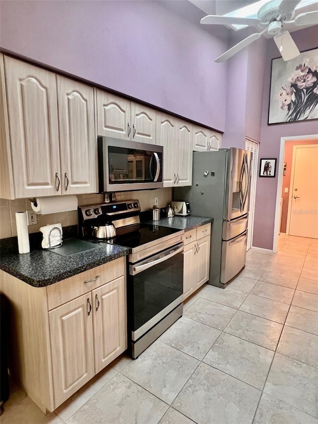 kitchen with light tile patterned floors, ceiling fan, a towering ceiling, stainless steel appliances, and light brown cabinetry