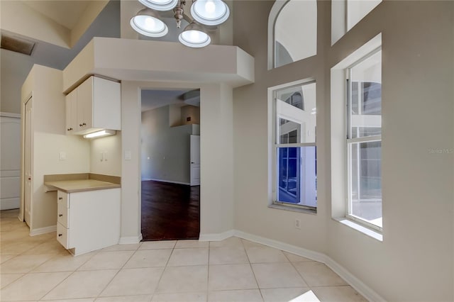 kitchen with a high ceiling, white cabinets, and light tile patterned flooring