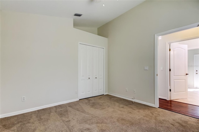 unfurnished bedroom featuring vaulted ceiling, carpet floors, and a closet